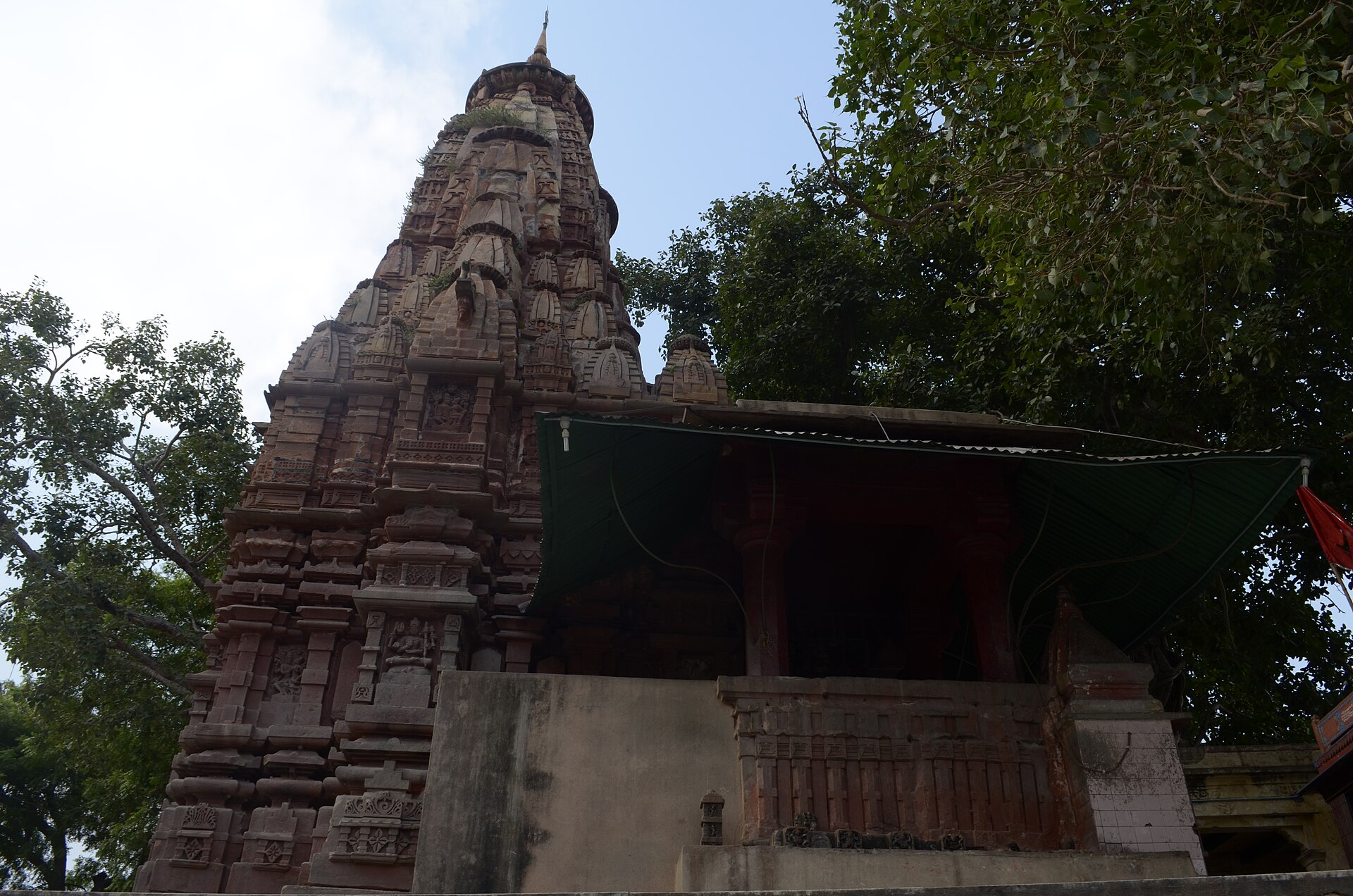 Kardmeshwar Mahadev at Kandwa: a carved sandstone spire beside a pillared hall, under old trees