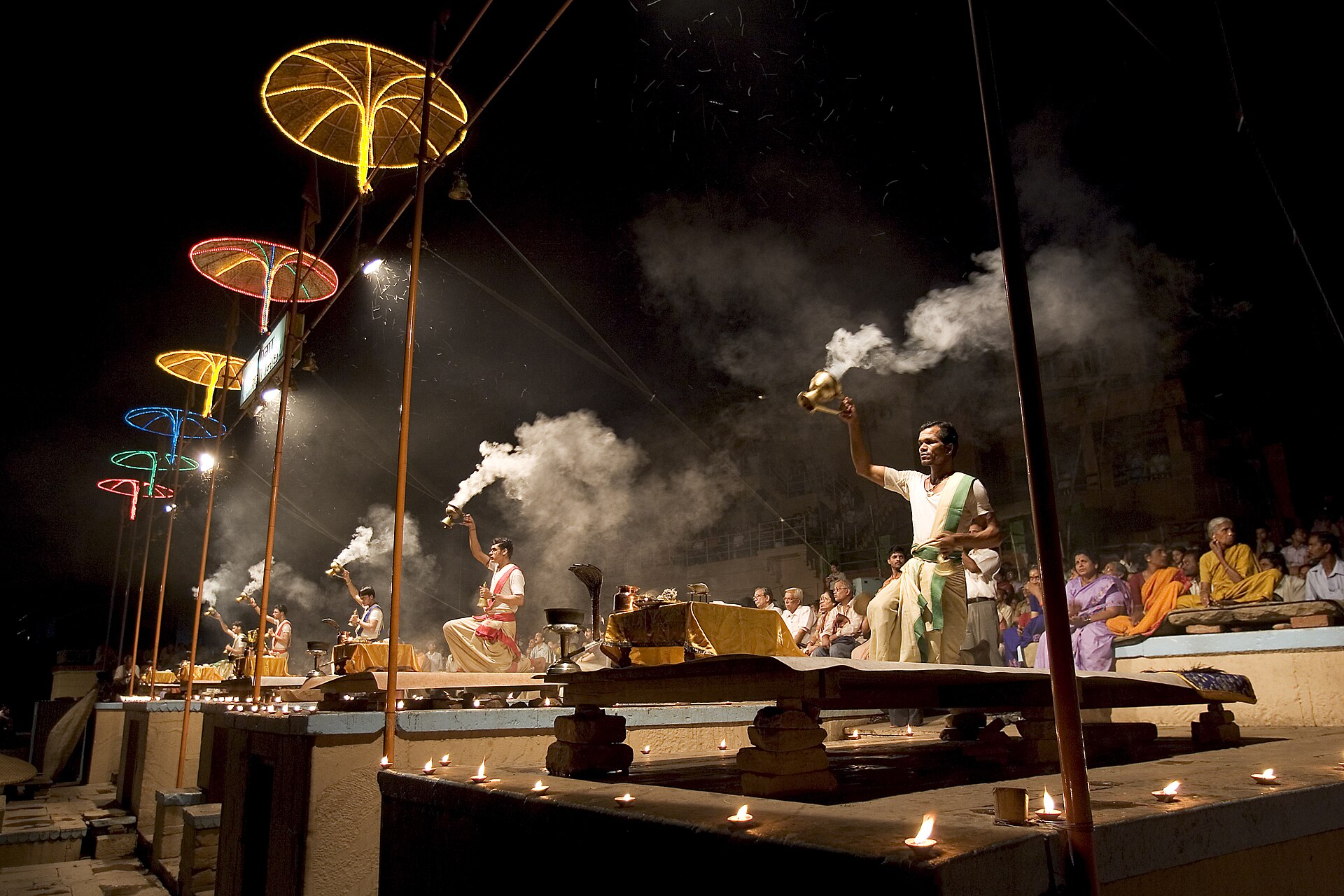Priests — the evening Ganga aarti, priests raising smoking lamps on the ghat, worshippers seated behind