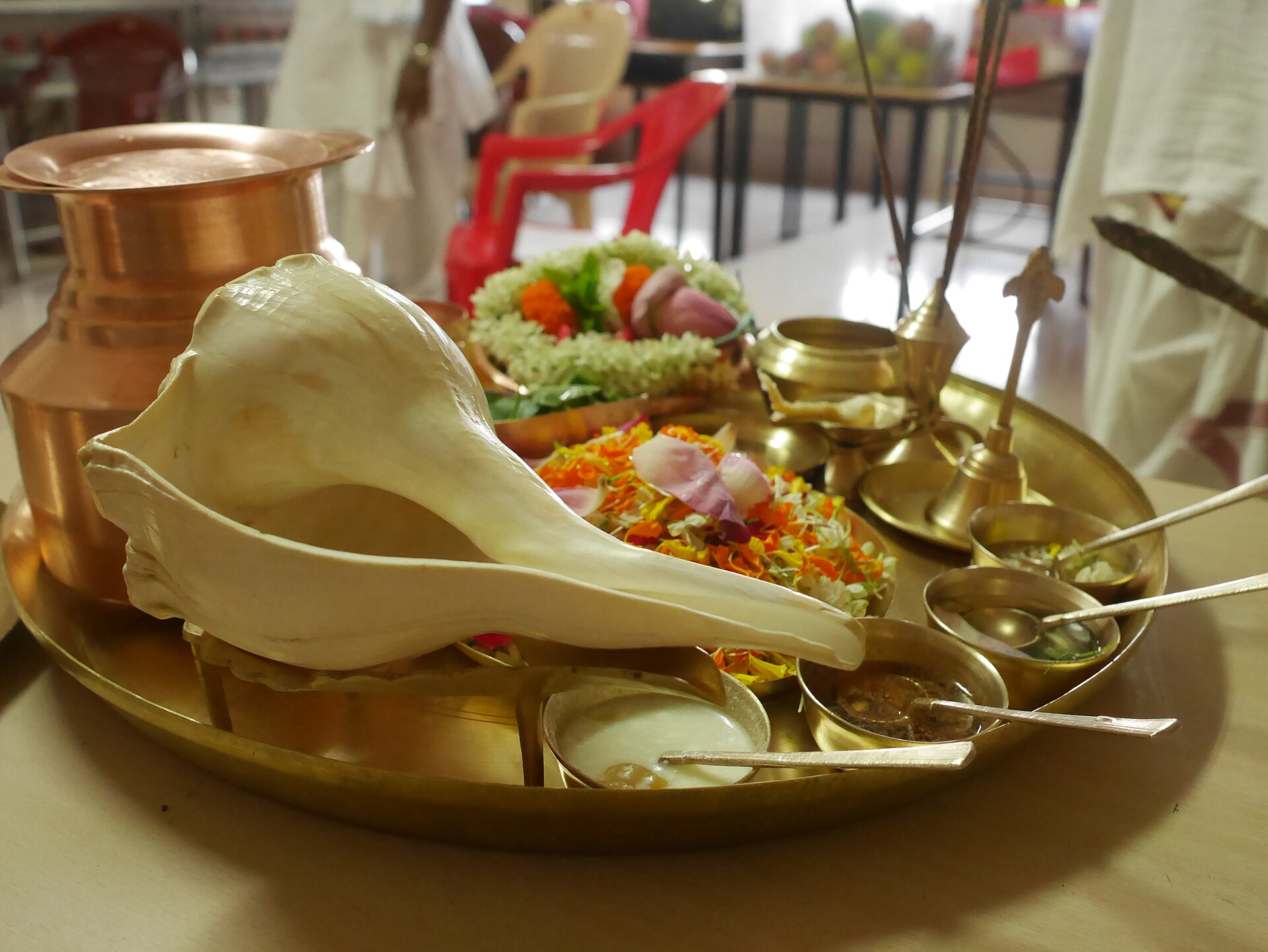 Puja materials — a brass worship tray with a conch, flowers, a copper lota and small bowls of offerings