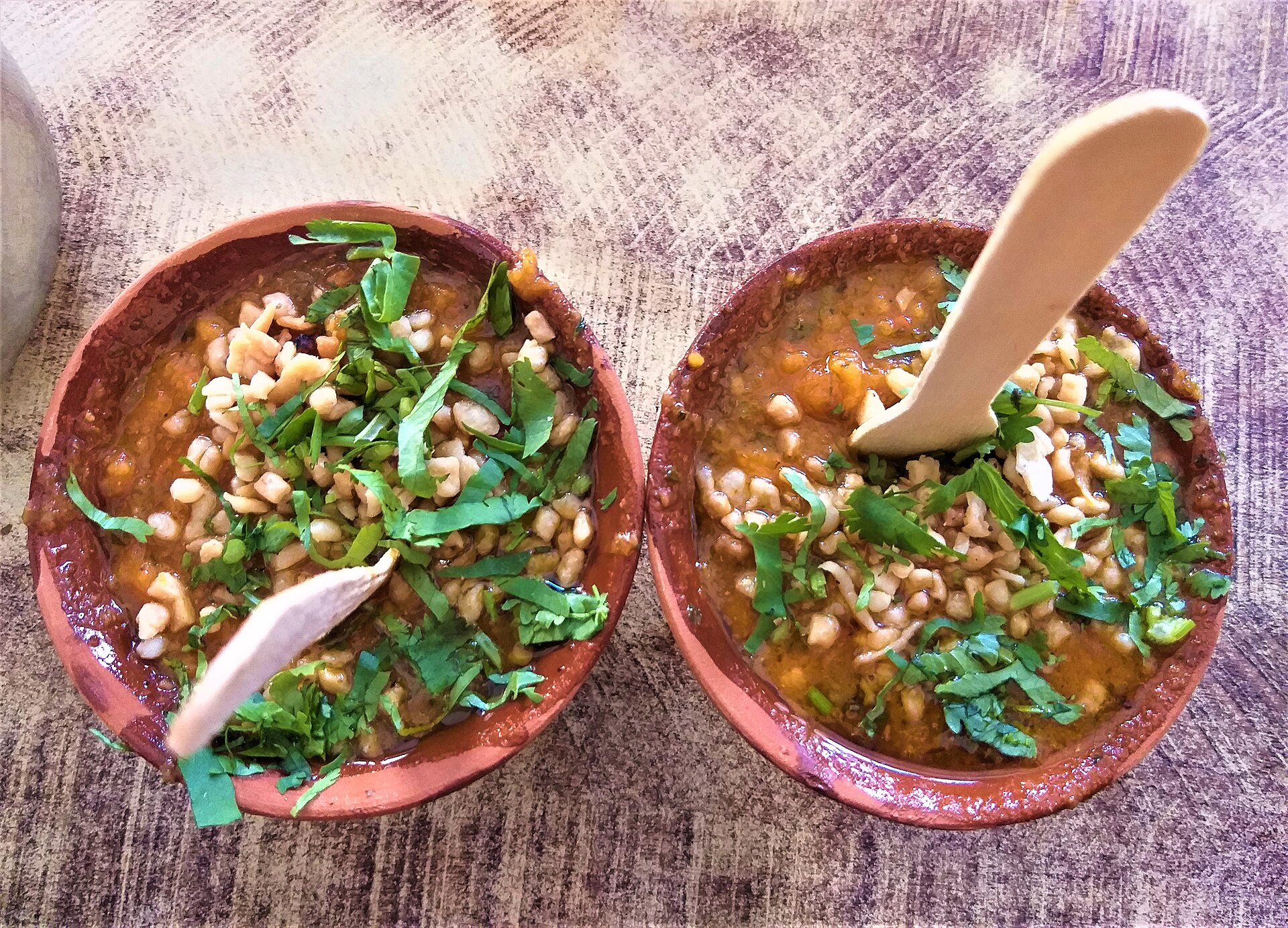 Tamatar chaat in two clay bowls topped with coriander and sev, the dish Kashi Chat Bhandar is known for
