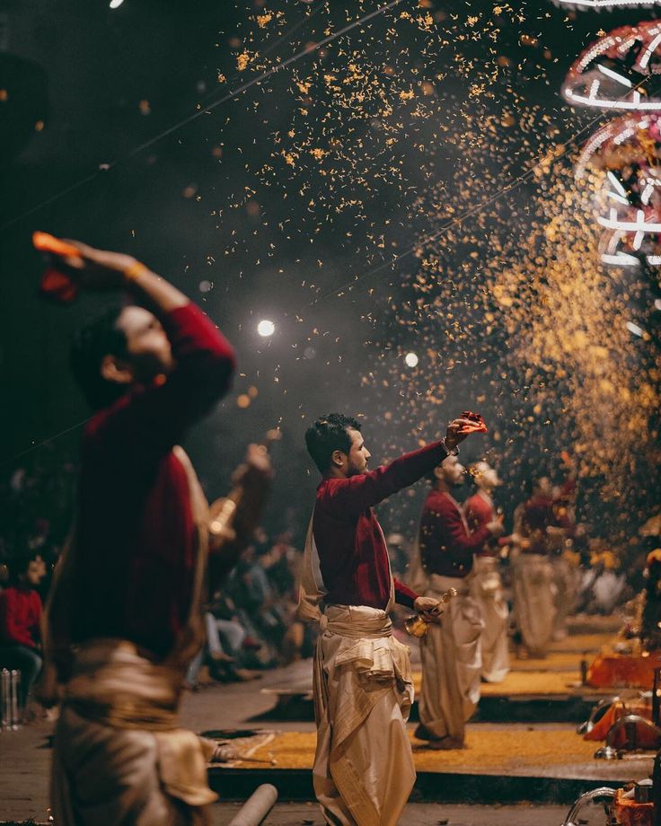 Ganga aarti — priests on raised platforms swinging tiered brass lamps, the crowd behind them